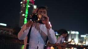 Two street musicians, a saxophonist and a guitarist play on the embankment of the night city. Beautiful evening landscape. stock footage Two street musicians, a saxophonist and a guitarist play on the embankment of the night city. Beautiful evening landscape. stock footage
