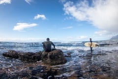 Surfers sit on the sea shore waiting to paddle out to surf the wave royalty free stock image Surfers sit on the sea shore waiting to paddle out to surf the wave royalty free stock image