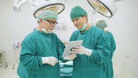Two surgeons reading a patient`s case history in operation room. stock video Two surgeons reading a patient`s case history in operation room. stock video