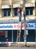 Two Thai electricians are fixing confusing electricity lines on a pole. stock photo Two Thai electricians are fixing confusing electricity lines on a pole. stock photo