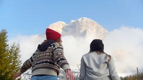 Two traveling happy young women jumping in front of the mountain stock footage Two traveling happy young women jumping in front of the mountain stock footage