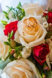 Two wedding gold rings with diamonds are on the bride's bouquet of red and white roses. stock image Two wedding gold rings with diamonds are on the bride's bouquet of red and white roses. stock image