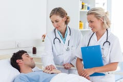 Two women doctors taking care of a patient stock photos Two women doctors taking care of a patient stock photos