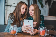 Two women talking in cafe drinking tea looking tablet stock image Two women talking in cafe drinking tea looking tablet stock image