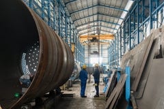 Two workers wearing yellow hard hat and blue uniform. In the interior of an industrial hall Royalty Free Stock Photos Two workers wearing yellow hard hat and blue uniform. In the interior of an industrial hall Royalty Free Stock Photos