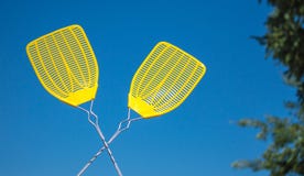 Two yellow fly swatters against a blue sky