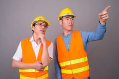 Two young Asian men construction worker together against gray ba royalty free stock photos Two young Asian men construction worker together against gray ba royalty free stock photos