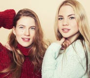 Two young girlfriends in winter sweaters indoors having fun. Lifestyle. Blond teen friends close up Royalty Free Stock Photography Two young girlfriends in winter sweaters indoors having fun. Lifestyle. Blond teen friends close up Royalty Free Stock Photography