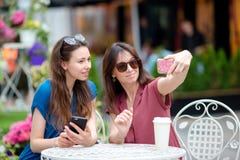 Two young girls taking selfie with smart phone at the outdoors cafe. Two women after shopping with bags sitting in royalty free stock photos Two young girls taking selfie with smart phone at the outdoors cafe. Two women after shopping with bags sitting in royalty free stock photos