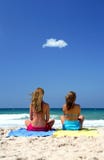Two young, healthy women sitting on a sunny beach