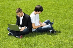 Two Young Men Sitting On Grass With Their Laptops Stock Photos