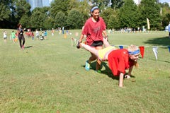 Two Young Women Compete In Wheelbarrow Race At Summer Fundraiser royalty free stock image Two Young Women Compete In Wheelbarrow Race At Summer Fundraiser royalty free stock image