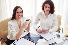 Two young women teamworking and drinking coffee in the office stock photos Two young women teamworking and drinking coffee in the office stock photos