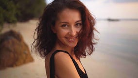 Tylny widok atrakcyjni długowłosy kędzierzawi brunetki kobiety zwroty kamera i daje pięknemu uśmiechowi zbiory Tylny widok atrakcyjni długowłosy kędzierzawi brunetki kobiety zwroty kamera i daje pięknemu uśmiechowi zbiory