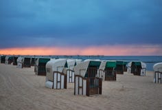 Typiska tyska korgar för strandstolar eller för strandstolar på stranden av Nord eller det baltiska havet i aftonen arkivbild Typiska tyska korgar för strandstolar eller för strandstolar på stranden av Nord eller det baltiska havet i aftonen arkivbild