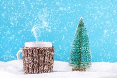 Tè caldo della bevanda di Natale in tazza con l'albero di abete della sciarpa e di natale della lana su neve immagini stock libere da diritti Tè caldo della bevanda di Natale in tazza con l'albero di abete della sciarpa e di natale della lana su neve immagini stock libere da diritti
