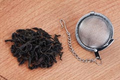 Tè nero e filtro del tè con la catena, su fondo di legno immagine stock Tè nero e filtro del tè con la catena, su fondo di legno immagine stock