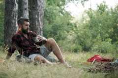 Tè o caffè della bevanda dei pantaloni a vita bassa al falò L'uomo barbuto si rilassa con la tazza a fuoco di accampamento Il tip fotografia stock libera da diritti Tè o caffè della bevanda dei pantaloni a vita bassa al falò L'uomo barbuto si rilassa con la tazza a fuoco di accampamento Il tip fotografia stock libera da diritti