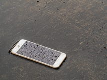 Téléphone intelligent humide laissé tomber sur le plancher d'inondation photos libres de droits Téléphone intelligent humide laissé tomber sur le plancher d'inondation photos libres de droits