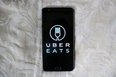Uber ест app на черном телефоне с белой предпосылкой текстуры стоковая фотография Uber ест app на черном телефоне с белой предпосылкой текстуры стоковая фотография