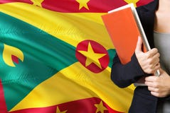 Uczyć się Grenadian językowego pojęcie Młodej kobiety pozycja z Grenada flagą w tle Nauczyciela mienia książki, pomarańcze obraz royalty free Uczyć się Grenadian językowego pojęcie Młodej kobiety pozycja z Grenada flagą w tle Nauczyciela mienia książki, pomarańcze obraz royalty free