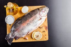 Uitgehaalde forel op een houten scherpe raad met ingrediënten voor het koken Hoogste mening stock afbeelding Uitgehaalde forel op een houten scherpe raad met ingrediënten voor het koken Hoogste mening stock afbeelding