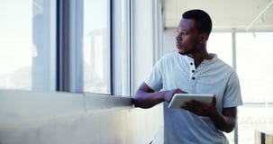 Uitvoerende macht die zich dichtbij venster bevinden en digitale tablet de gebruiken stock videobeelden Uitvoerende macht die zich dichtbij venster bevinden en digitale tablet de gebruiken stock videobeelden