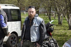 UKRAINE, SHOSTKA - APRIL 28,2018: Ein Radfahrer des jungen Mannes mit einem Bart und in der Denimweste im Shostka-Stadt-Park lizenzfreie stockfotografie UKRAINE, SHOSTKA - APRIL 28,2018: Ein Radfahrer des jungen Mannes mit einem Bart und in der Denimweste im Shostka-Stadt-Park lizenzfreie stockfotografie