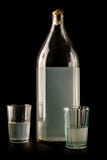 Ukrainian national drink. The big bottle of moonshine isolated on a black background. Old bottle and glass with russian royalty free stock images Ukrainian national drink. The big bottle of moonshine isolated on a black background. Old bottle and glass with russian royalty free stock images