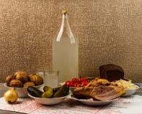 Ukrainian national drink and snack. The big bottle and glass of moonshine on the old wooden table. Russian vodka and snack. Stock Photography Ukrainian national drink and snack. The big bottle and glass of moonshine on the old wooden table. Russian vodka and snack. Stock Photography