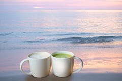 Um copo do café quente e um copo do chá verde quente na praia imagens de stock royalty free Um copo do café quente e um copo do chá verde quente na praia imagens de stock royalty free