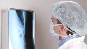Um doutor novo examina os resultados de um raio X paciente do ` s na parede Analisa do tórax e dos reforços video estoque Um doutor novo examina os resultados de um raio X paciente do ` s na parede Analisa do tórax e dos reforços video estoque