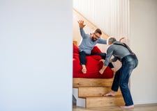 Um filho adulto do moderno e um pai superior dentro em casa, tendo o divertimento imagens de stock Um filho adulto do moderno e um pai superior dentro em casa, tendo o divertimento imagens de stock