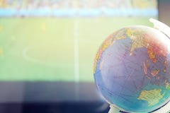 Um globo pequeno com um fundo borrado do campo de futebol imagem de stock Um globo pequeno com um fundo borrado do campo de futebol imagem de stock