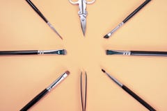 Um grupo de escovas diferentes do maquilhador, a pinça e as tesouras encontram-se em um círculo com copyspace para o texto na cor fotografia de stock royalty free Um grupo de escovas diferentes do maquilhador, a pinça e as tesouras encontram-se em um círculo com copyspace para o texto na cor fotografia de stock royalty free