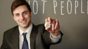 Um homem de negócios em um terno realiza em sua mão um bitcoin de prata filme Um homem de negócios em um terno realiza em sua mão um bitcoin de prata filme