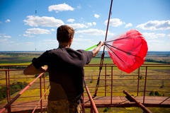 Um homem está preparando um paraquedas vermelho para o salto baixo foto de stock royalty free Um homem está preparando um paraquedas vermelho para o salto baixo foto de stock royalty free