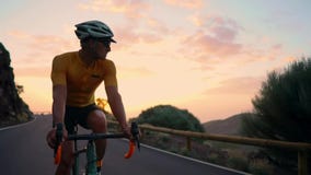 Um homem nos passeios de uma bicicleta que olham a câmera no por do sol em uma estrada da montanha Movimento lento Steadicam vídeos de arquivo Um homem nos passeios de uma bicicleta que olham a câmera no por do sol em uma estrada da montanha Movimento lento Steadicam vídeos de arquivo