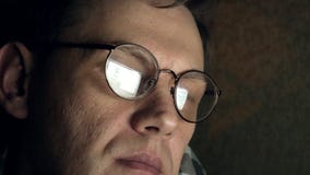 Um homem nos vidros trabalha tarde na noite Olha preocupado, ele vê no tela de computador na frente dele, um close-up filme Um homem nos vidros trabalha tarde na noite Olha preocupado, ele vê no tela de computador na frente dele, um close-up filme