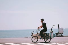 Um homem novo que biking para surfar no mar imagem de stock royalty free Um homem novo que biking para surfar no mar imagem de stock royalty free