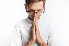 Um homem novo que reza ao deus ou ao Jesus Christ, dobrado, em um fundo branco, pedindo a ajuda imagem de stock Um homem novo que reza ao deus ou ao Jesus Christ, dobrado, em um fundo branco, pedindo a ajuda imagem de stock