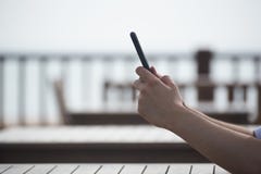 Um homem que guarda o telefone celular e que senta-se perto da praia fotografia de stock Um homem que guarda o telefone celular e que senta-se perto da praia fotografia de stock