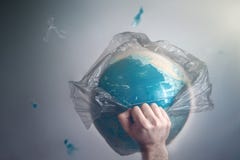 Um homem quebra um saco de lixo que seja globo envolvido da terra do planeta O conceito da ecologia e poluição do cerco imagem de stock Um homem quebra um saco de lixo que seja globo envolvido da terra do planeta O conceito da ecologia e poluição do cerco imagem de stock