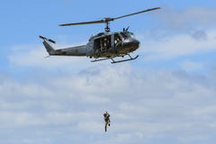Um homem winched para baixo de um helicóptero do Iroquois de Bell fotos de stock Um homem winched para baixo de um helicóptero do Iroquois de Bell fotos de stock