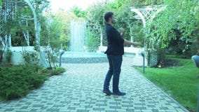 Um homem à moda novo dança no parque para a alegria Um homem de negócios bem sucedido comemora sua vitória Dá a rédea livre a filme Um homem à moda novo dança no parque para a alegria Um homem de negócios bem sucedido comemora sua vitória Dá a rédea livre a filme