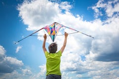 Um menino com um papagaio colorido em suas mãos contra o céu azul com nuvens Fotografia conceptual imagens de stock Um menino com um papagaio colorido em suas mãos contra o céu azul com nuvens Fotografia conceptual imagens de stock