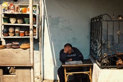 um oleiro do homem que lê um jornal em uma mesa ao esperar clientes para seus produtos foto de stock royalty free um oleiro do homem que lê um jornal em uma mesa ao esperar clientes para seus produtos foto de stock royalty free