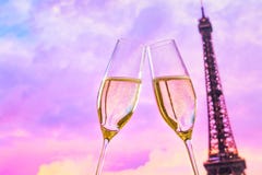 Um par de flautas de champanhe com bolhas douradas no por do sol borra o fundo de Eiffel da torre imagem de stock royalty free Um par de flautas de champanhe com bolhas douradas no por do sol borra o fundo de Eiffel da torre imagem de stock royalty free
