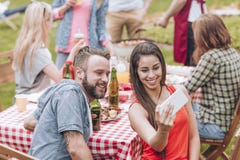 Um par novo que toma uma foto do selfie em um BBQ do fim de semana party saídas fotografia de stock Um par novo que toma uma foto do selfie em um BBQ do fim de semana party saídas fotografia de stock