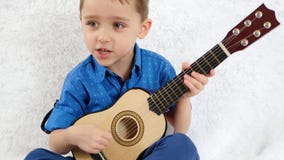 Um rapaz pequeno joga uma guitarra acústica das crianças e canta uma música Música, a educação das crianças O conceito de um feli vídeos de arquivo Um rapaz pequeno joga uma guitarra acústica das crianças e canta uma música Música, a educação das crianças O conceito de um feli vídeos de arquivo